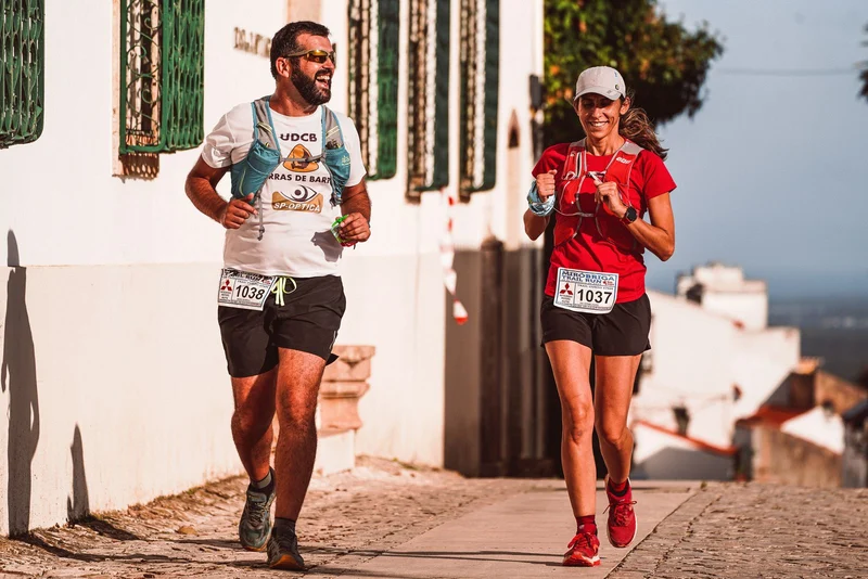 Uma mulher e um homem sorrindo durante uma prova de corrida